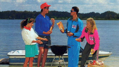 Friends gathering around grill with Correct Craft boat behing them